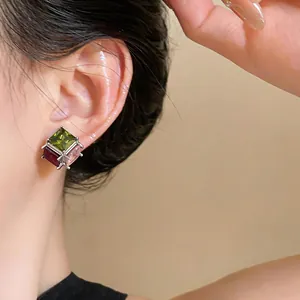 Detailed macro view of elegant square stud earrings with colorful cubic zirconia on ear
