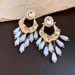 Vintage gold-toned earrings featuring hammered texture and white teardrop pearl tassels