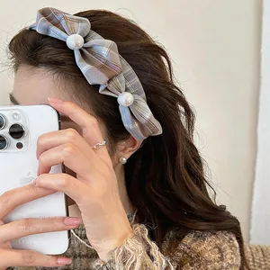 Détail d'une pince à cheveux à nœud écossais bleu avec perles sur modèle