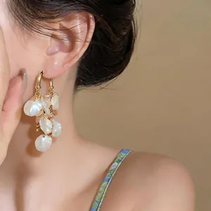 Close-up of elegant French style earrings with pearl-like petal tassels on gold hoops.