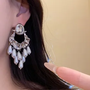 Close-up of elegant vintage silver-tone earrings with oval crystal and pearl tassels