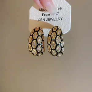 Close-up of vintage-style 18k gold plated earrings with hexagonal zircon honeycomb pattern
