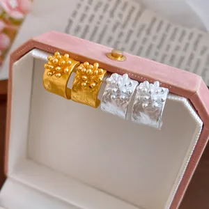 Vista dettagliata degli orecchini a fiore a forma di C in oro e argento in box