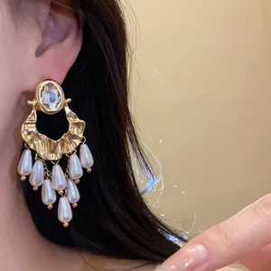 Close-up of vintage gold earrings with oval rhinestones and white pearl tassels