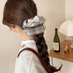 Détail d'une pince à cheveux torsadée à carreaux bleus avec un joli nœud en dentelle