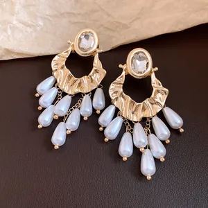Macro view of vintage gold-tone earrings with oval rhinestones and teardrop pearl tassels.