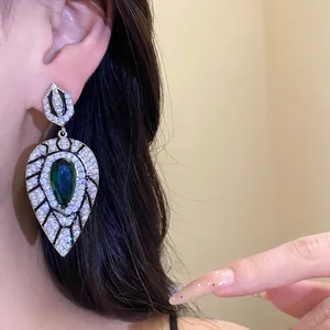 Nahaufnahme eleganter Tropfenohrring mit grünem Zirkon und Kristallen am Model