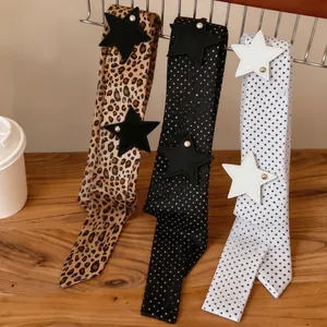 Three leopard and polka dot print scarves with leather star patches on a display