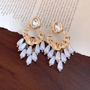 Detail of vintage gold earrings with oval rhinestones and teardrop pearl tassels