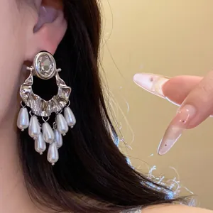 Close-up detail of vintage silver earrings featuring an oval crystal and pearl tassels.