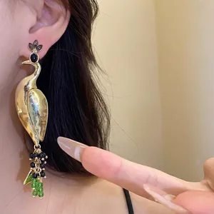 Exaggerated gold peacock pendant earrings with vintage green beads and artistic design