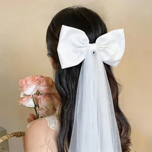 Detailed view of a large white satin bow hair clip with an elegant long tulle mesh veil
