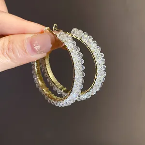 Close-up of gold-plated hoop earrings featuring intricate clear crystal bead wrap.