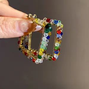Close-up of vibrant square hoop earrings with multi-colored faceted glass beads detailing
