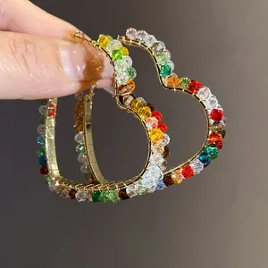 Close-up detail of colorful glass beads wrapped on gold heart-shaped hoop earrings