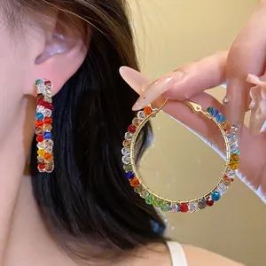 Detailed view of large gold-tone hoop earrings with vibrant faceted colorful glass beads