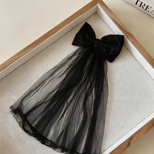 Detail view of a black fabric bow hair clip featuring a delicate long tulle mesh veil