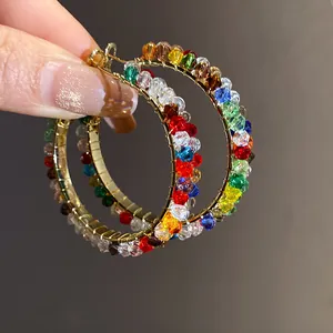 Detailed view of handmade gold hoop earrings with vibrant multi-colored glass crystals