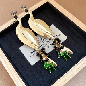 Detailed macro view of vintage golden peacock drop earrings with elegant green beads