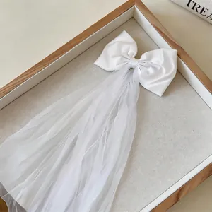 Detailed macro view of elegant white fabric bow hair clip with a long tulle mesh veil