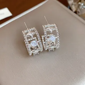 Dettaglio ravvicinato di orecchini a stella in argento con zircone e bordo perlato