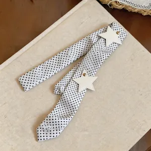 Detailed view of the polka dot pattern and white star leather patches on the skinny scarf