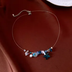 Dettaglio di una collana minimalista con ciondolo a stella marina e perla su raso marrone