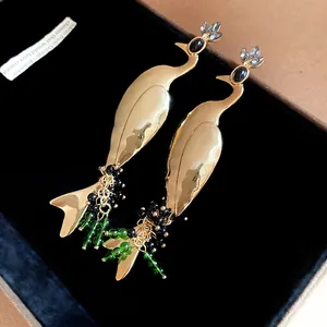 Macro detail of vintage golden peacock drop earrings with green beads and crystals