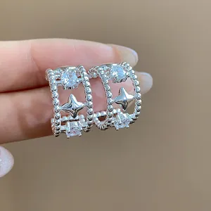 Dettaglio ravvicinato di orecchini a cerchio in argento a forma di stella con zirconi