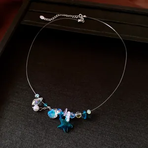 Dettaglio ravvicinato di ciondolo a stella marina blu e perla su collana invisibile