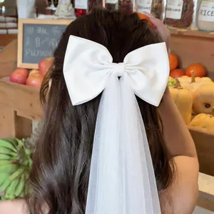 Detailed back view of a elegant white fabric bow hair clip with long tulle ribbon tassel
