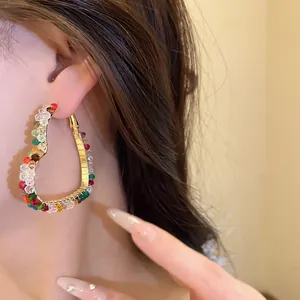 Detailed view of elegant colorful glass beaded heart hoop earrings worn by a model