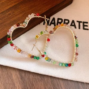 Macro shot showing colorful glass beads wrapped around golden heart hoop earrings