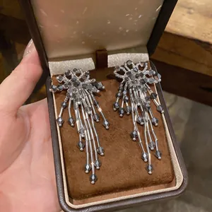 Close-up view of elegant silver flower tassel earrings presented in a brown jewelry box.