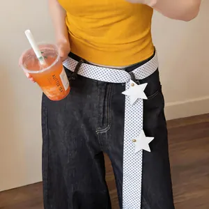 Stylish white polka dot scarf used as a belt with star charms on dark denim jeans