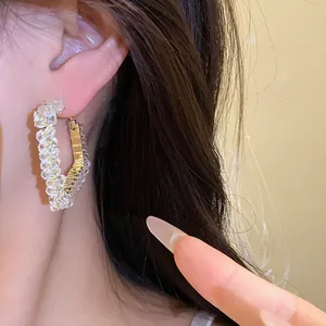 Detailed close-up showing the shimmering glass beads on luxury gold-tone hoop earrings