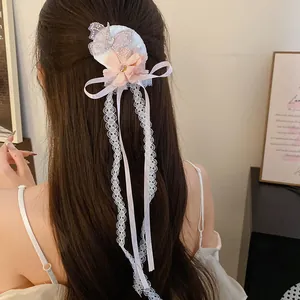 Elegante stoffen haarklem met strass vlinder en witte kant kwastjes getoond op haar