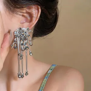 Close-up detail of elegant silver geometric beaded long tassel earrings worn by a model