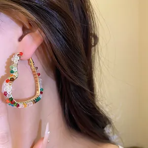 Close-up of colorful glass bead heart-shaped hoop earring worn on ear