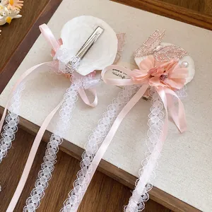 Detailweergave van haarspeld met roze stoffen bloem, strasvlinder en witte kantlinten