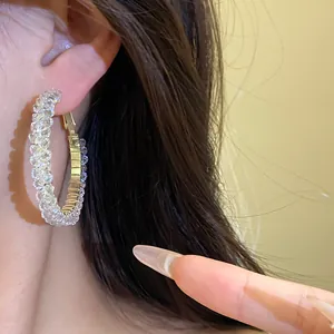 Close-up detail of luxury sparkling glass crystal hoop earrings worn on a model ear.