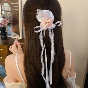 Detail van roze bloem vlinder haarclip met kanten kwastje op lang donker bruin haar
