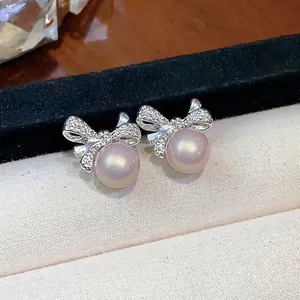 Elegantes pendientes de perlas con lazo en tono plateado y detalles brillantes en bandeja