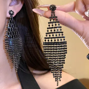 Detailed view of elegant black rhinestone diamond-shaped tassel earrings worn by model.