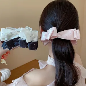 Elegant fabric polka dot bow hair clip worn by a model in a sweet and graceful style.