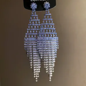 Close-up of elegant silver needle diamond tassel earrings with purple gradient crystals.