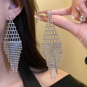 Detailed close-up of sparkling rhinestone rhombus tassel earrings worn by a model person.