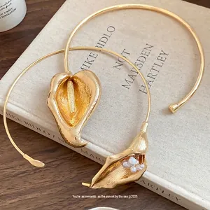 Vintage gold floral choker necklace with pearl accent on artistic book background.