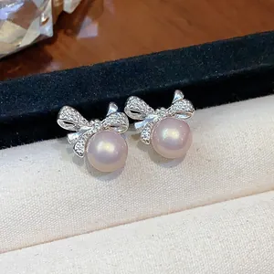 Primer plano de elegantes pendientes de lazo plateados con perlas rosas y circón