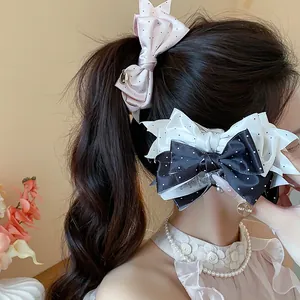 Close-up view of elegant polka dot bow hair clips on a model's ponytail and side hair.